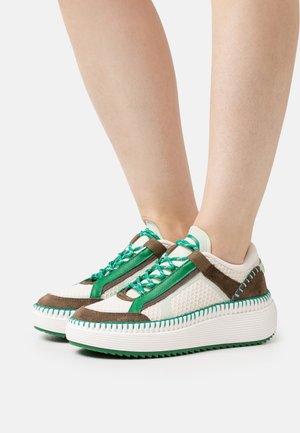 Tenisky s kombinací bílé síťoviny, hnědé semiše a zelených akcentů. Silná bílá podrážka s texturovanými drážkami a jedinečným designem tkaniček.