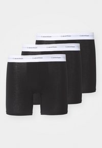 Tre paia di boxer neri in cotone con elastico nella vita brandizzato Calvin Klein, caratterizzati da una texture liscia e un design aderente.