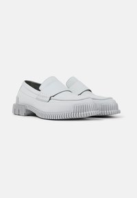 Scarpe slip-on bianche in pelle con suola in gomma spessa, caratterizzate da dettagli scanalati e superfici lisce, progettate per comfort e durata.