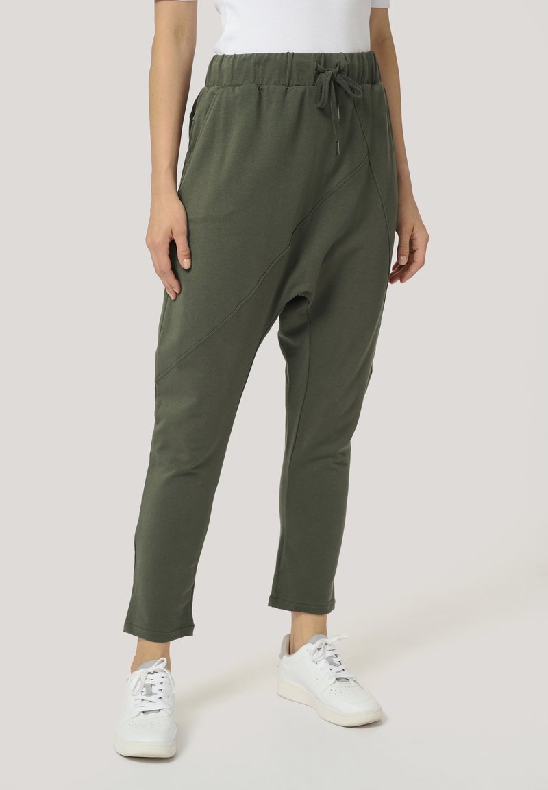 Groene joggers gemaakt van zachte stof met een elastische tailleband, trekkoord en taps toelopende benen. Kenmerkt schuine naden en zijzakken.