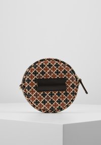 Runde Reißverschlusstasche in Braun, Schwarz und Creme mit einem geometrischen Muster. Verfügt über ein flaches, schwarzes Lederrechteck-Akzent auf der Vorderseite.