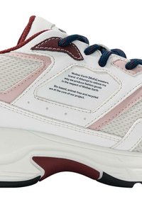 Sneaker bianco con accenti in rete, dettagli rosa e maroon, e lacci blu. Presenta materiale bio-based e un'etichetta attaccata con testo eco-sostenibile.