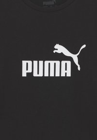 Černé bavlněné tričko s velkým bílým logem PUMA a grafikou skákajícího pumy. Design s kulatým výstřihem a hladkou texturou.
