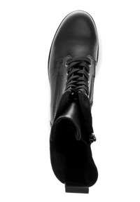 Bottine en cuir noir avec bout rond, coutures verticales et fermeture à lacets sur le devant ; elle possède un panneau en suède texturé et une languette de tirage au talon.