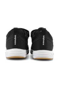 Ett par svarta sneakers med vita sulor och bruna mönster, sedd bakifrån, med en dragflik med vit varumärkestext.