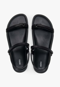 Zwarte sandalen met twee dunne banden en een brede, gladde zool. Heeft een minimalistisch ontwerp met een logo aan de zijkant.