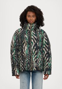 Veste rembourrée en imprimé zèbre multicolore avec du vert, du noir et du beige. Dotée d'un col haut et d'une fermeture éclair dorée.