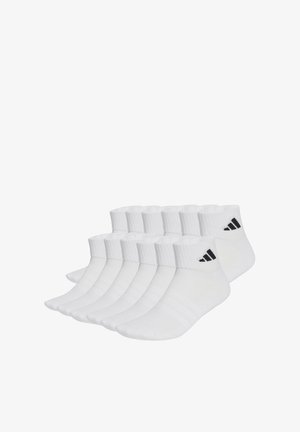 Dix paires de chaussettes blanches courtes avec le logo Adidas noir sur les bords côtes, disposées soigneusement côte à côte sur un fond blanc.