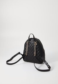 Schwarzer, gesteppter Rucksack mit Kettenakzenten, goldenen Beschlägen und runder Form. Verfügt über zwei Griffe und verstellbare Schulterriemen.
