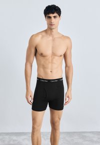 Bóxer negros con una cinturilla con la marca "Calvin Klein". La tela parece suave y elástica, con un diseño ajustado.