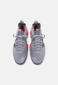 Gray athletic shoes with red accents, mesh upper, cushioned sole, and traditional lace-up design. Features a pull tab on the heel.