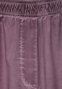 Lila satinbyxor med elastisk midja och sidoficka. Slät textur med en subtil lyster och synliga sömdetaljer.