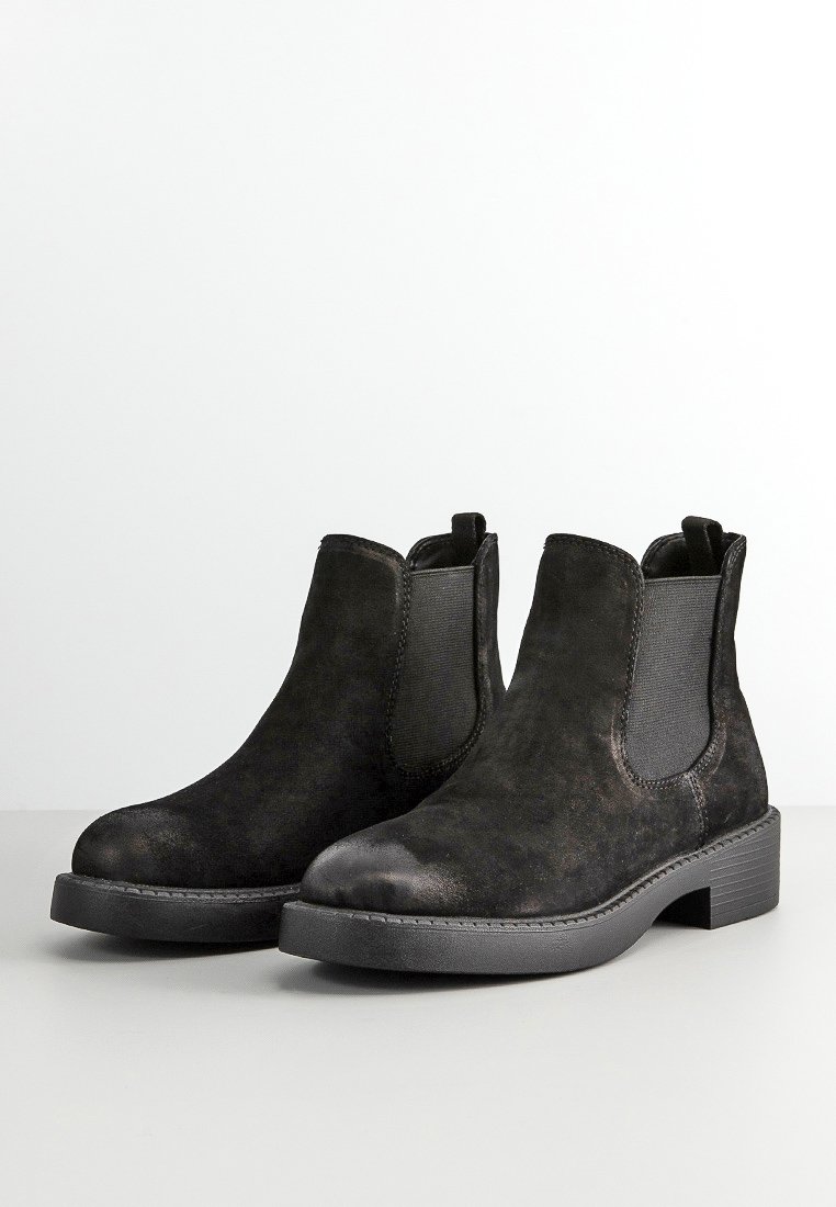 Botas Chelsea de ante negro con paneles elásticos en los lados, punta redondeada y una suela de goma resistente. Textura suave con un acabado mate.