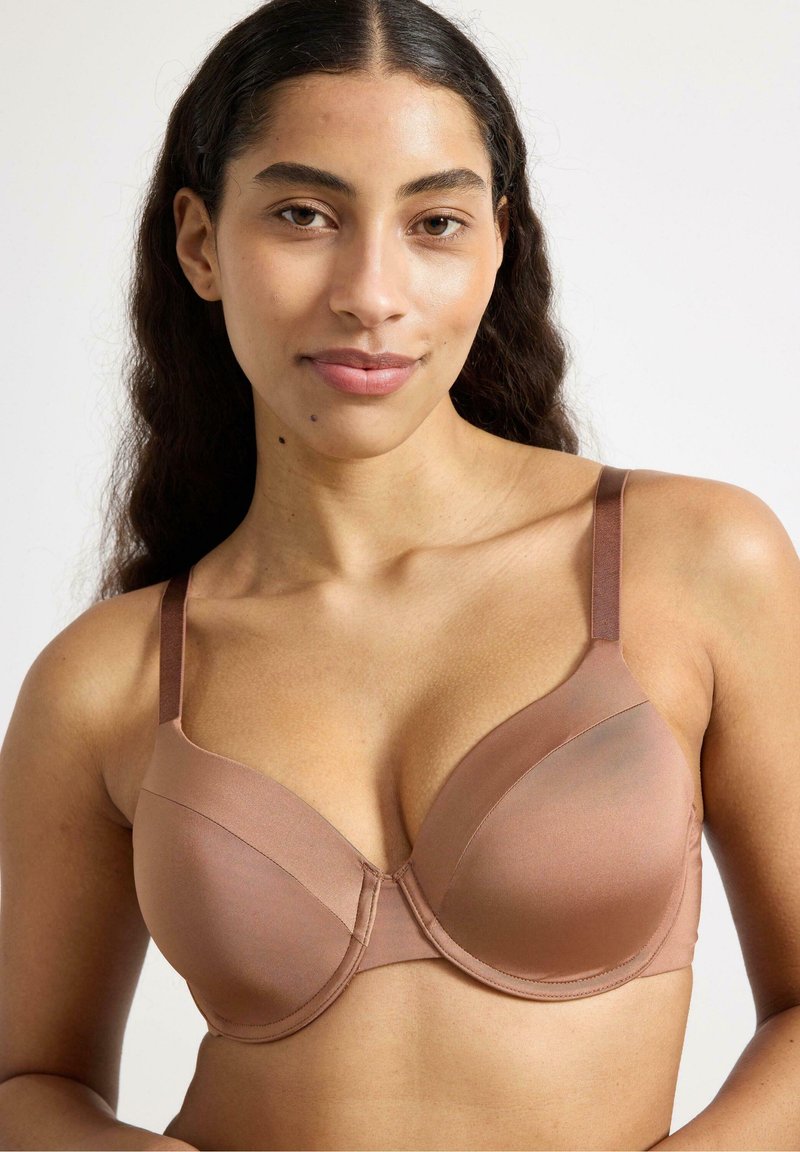Reggiseno marrone con ferretto, realizzato in tessuto morbido, con spalline regolabili e design senza cuciture. Presenta una leggera lucentezza e coppe sagomate.