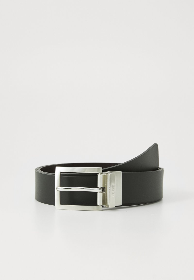 Cinturón de cuero negro con una hebilla rectangular de plata brillante, que cuenta con un cierre de púa seguro y una textura suave.