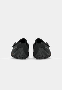 Crne atletske cipele s teksturiranim gornjim dijelom, čičak trakom i uzorkovanim gumiranim potplatom koji sadrži Merrell logo i Vibram brendiranje.
