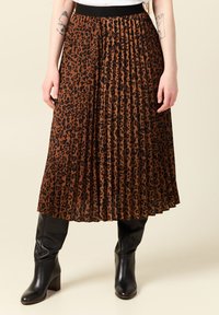 Gonna midi plissettata marrone con stampa leopardata nera. Presenta una vita elastica e si abbina a stivali neri con tacco.