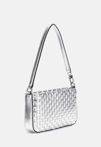 Metaliczna srebrna pleciona torba o smukłym kształcie, z odpinanym paskiem i błyszczącymi elementami wykończenia. Gładka, lustrzana tekstura.