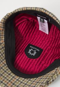 Wool blend hat with a textured, multicolored exterior. Interior features a smooth, pink lining and a black label with the brand "Brixton."