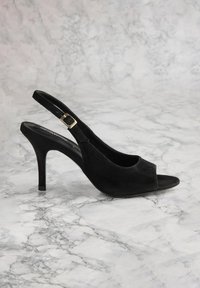 Zwarte suède slingback-pumps met open teen, met een slanke hak en een verstelbare gesp. Glad materiaal met minimale accenten.