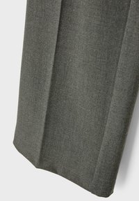 Pantalon en tissu gris foncé sur mesure avec un pli net courant verticalement au centre.