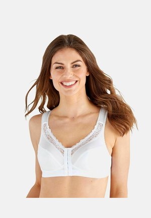 Lachende vrouw met lang haar die een witte beha met vooraan sluiting draagt, met kanten rand aan de bandjes en halslijn.