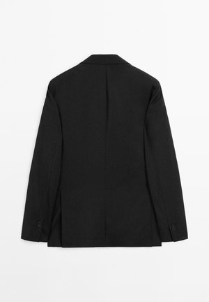 Czarna strukturalna marynarka z klapami, długimi rękawami i pojedynczym rozcięciem z tyłu. Tkanina wydaje się gładka i dopasowana.