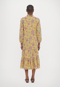 Kollane lillemusteriga kleit, millel on roosa ja halli aktsendid, pikad varrukad, volangiga krae ja kihiline hemline. Materjal näeb välja kerge ja tekstuurne.