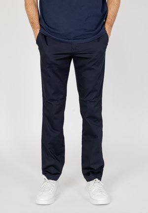 Pantaloni blu realizzati in tessuto liscio con taglio dritto, dotati di tasche laterali e abbinati a sneakers bianche.