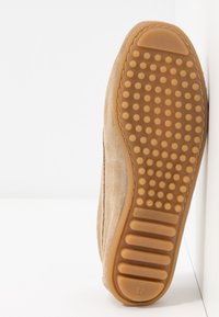 Semelle de chaussure en daim beige avec une semelle extérieure en caoutchouc comportant des grips ronds et rectangulaires pour l'adhérence, taille indiquée 37 au talon.