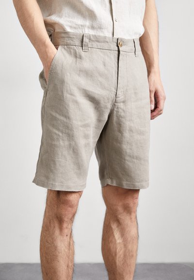 Shorts en lin beige avec une coupe droite, poches latérales et une fermeture bouton à la taille, présentant une texture lisse et un design minimaliste.