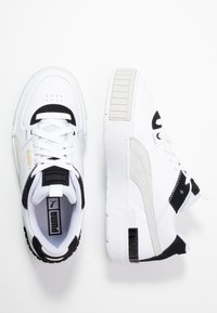 Białe i czarne sneakersy Puma z sznurówkami, złotym logo i textured soles, pokazane z góry i z boku na białym tle.