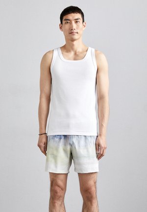 Hvit bomull tanktopp, kombinert med korte badeshorts med et akvarellmønster i blått og grønt. Enkelt design, avslappet passform.