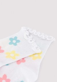 Calcetines blancos hasta el tobillo con bordes fruncidos, decorados con patrones de flores pastel multicolores en azul, amarillo y rosa.