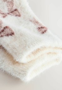 Pehmeä kermaisen värinen huopa, jossa on pehmeä tekstuuri ja hennot ruskeat kuviot. Väännetty, esittelee paksua, mukavaa muotoilua ja ylellistä materiaalia.