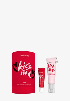 Røde og lyserøde tuber med Alessandro Kiss Me håndcreme og neglesmør ved siden af en matchende rød cylindrisk gaveæske.