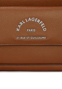 Rudas tekstūruotas odinis piniginė su įspaustu sidabriniu logotipu "KARL LAGERFELD PARIS" ir adresu "21 RUE ST-GUILLAUME" centre.