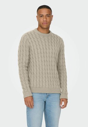 Beige kabelgebreide trui met een ronde halslijn en geribde manchet. Gemaakt van een textuurstof, met een verheven patroon overal.