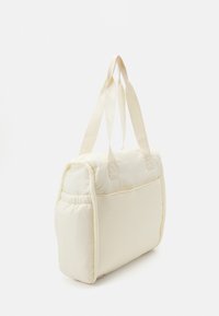 Sac en forme de rectangle de couleur crème, avec un tissu doux, deux poignées et un détail froncé au bas.