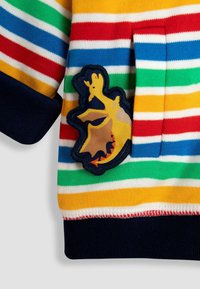 Sudadera a rayas en amarillo, verde, rojo, azul y blanco. Presenta un puño en navy y un parche de dragón amarillo con acentos marrón y naranja.