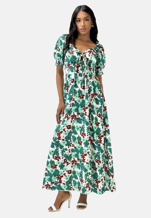 Robe maxi florale en vert, blanc et bordeaux. Présente des manches bouffantes, un détail à nouer et un corsage smocké. Le matériau semble léger et fluide.