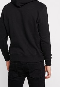 Czarny sweatshirt z kapturem, z kieszenią kangurką, ściągaczami na rękawach i u dołu. Miękka faktura tkaniny, z przestronnym kapturem i minimalistycznym designem.