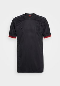 Maglietta da calcio nera a maniche corte, con 3 strisce sulle spalle, accenti rossi e gialli sui polsini, presenta un emblema e 4 stelle sul petto.