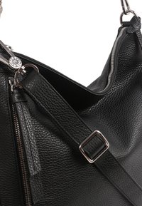 Sac à main en cuir noir avec une finition texturée, doté de quincaillerie en argent, d'une fermeture éclair et d'une sangle ajustable.
