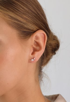 Kleine Ohrstecker aus Silber mit einem Design in Marquise- und Rundschliff, das mit einem funkelnden Finish versehen ist. Die Ohrstecker sitzen nah am Ohrläppchen.