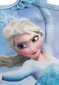 Maglione a tema Frozen con un'immagine di un personaggio con capelli biondo chiaro e occhi blu, su uno sfondo azzurro chiaro decorato con fiocchi di neve.