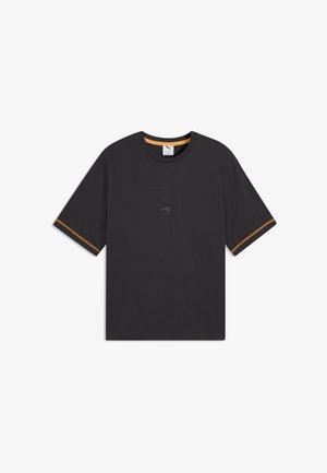 Camiseta negra de manga corta con cuello redondo, ribete interior del cuello en naranja, costuras naranjas en las mangas y sutiles logotipos de Puma y McLaren en el frente.
