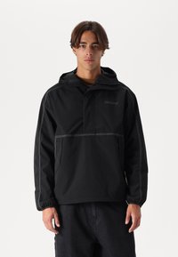 Black hooded jacket with a front pocket, featuring contrasting stitching and a logo on the chest. Lightweight fabric with a relaxed fit.