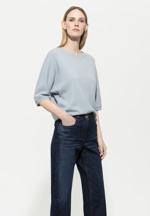 Light blue, short-sleeve sweater in soft material; paired with high-waisted, dark blue denim jeans featuring front pockets and stitching details.