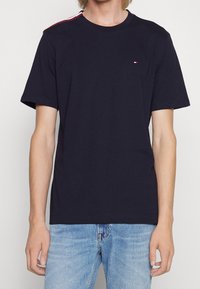 Męska granatowa koszulka z bawełny, z krótkim rękawem, okrągłym dekoltem i małym haftowanym logo na piersi.